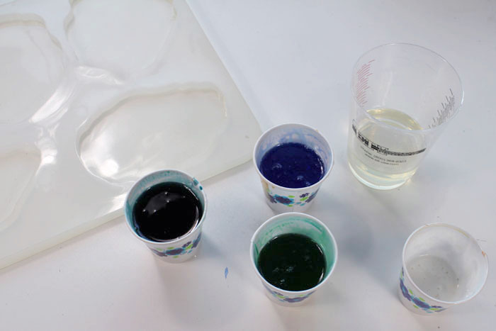 Step 2: Mix Agate Slice Color Then add about 4 drops of blue dye in one cup. Next, 4 drops of green dye in another cup. Then mix 2 drops of blue and 2 drops of green in the third cup. Add some white pigment in the last small cup and leave the mixing cup with clear resin.
