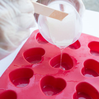 Resin being poured into a heart-shaped silicone mold.