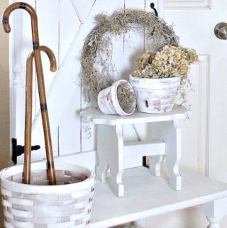 Farmhouse-Hall-Tree-Painted-apple-basketswoven-tall-basket-with-canes-farmhouse-stools-with-aged-pots-and-moss-wreath-blankets