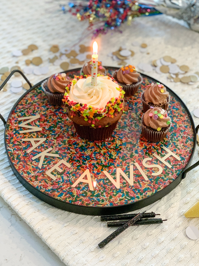Learn how to make a DIY rainbow sprinkles resin tray with this fun tutorial! EnviroTex Lite pour over resin makes it easy to create a festive serving tray for birthday cakes or cupcakes. They sit atop a layer or rainbow sprinkles!
