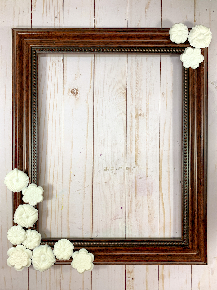 Resin embellishments made with FastCast resin are hot glued to a picture frame.