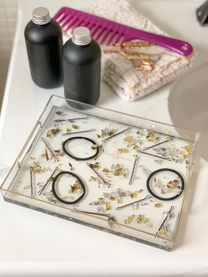 Make a DIY resin tray filled with hair accessories like bobby pins and ponytail elastics. This is the cutest DIY vanity tray around!
