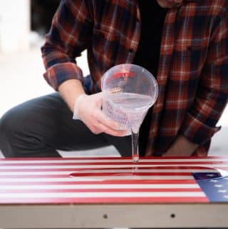 pouring amazing clear cast onto american flag cornhole board