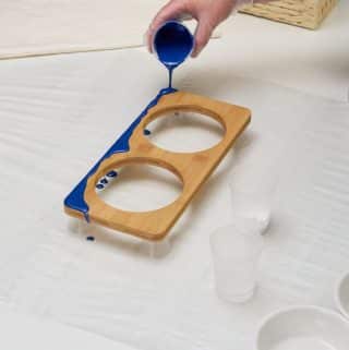 Blue resin being poured on a wooden base to make ocean resin art.