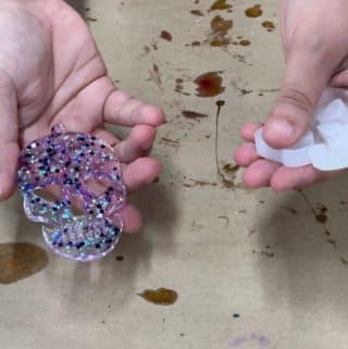 Purple glittery skull custom magnet being demolded.