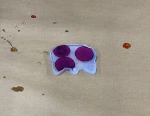 Purple alcohol ink dots spreading in resin in a cat mold.