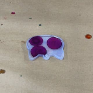 Purple alcohol ink dots spreading in resin in a cat mold.