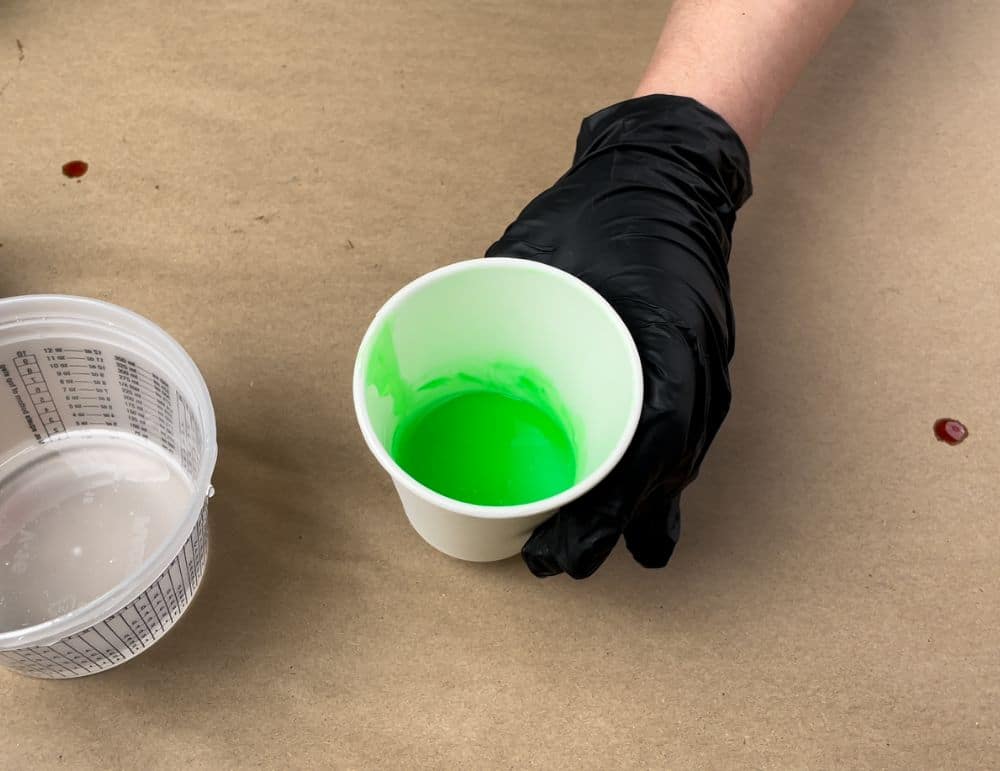 Glow in the dark powder and green resin dye mixed in a cup.