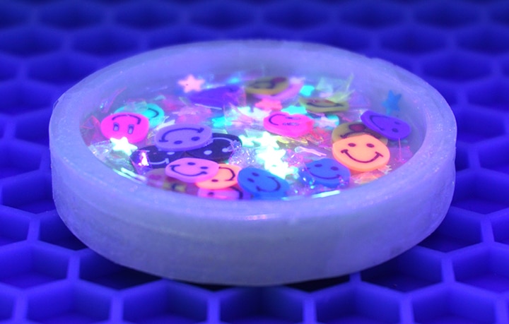 "Happy" Resin Shaker Charm under UV light